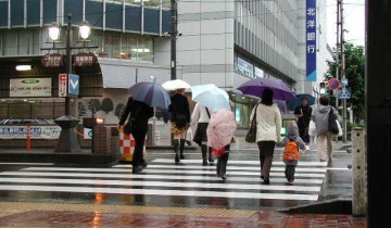雨降り、傘の花咲く駅前通